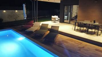An outdoor pool area with lounge chairs and a dining table.