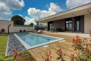 A modern outdoor pool area with a wooden deck, lounge chairs, and a covered seating area. - Villa Gigi With Private Pool (Visnjan)