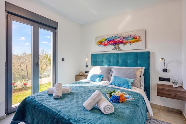 A bedroom with a large bed, a view through a sliding door, a painting on the wall, and a bedside table with a lamp. - Villa Gigi With Private Pool (Visnjan)