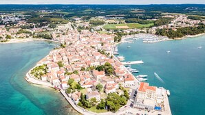 An aerial view of a coastal town with a marina, buildings, and clear blue waters.