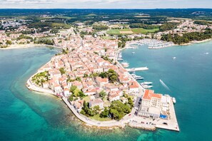 Vue aérienne d’une ville côtière avec un port de plaisance, des bâtiments et des eaux d’un bleu limpide.