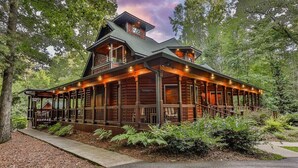 A log cabin-style building with a porch, multiple windows, and a chimney. - Mountain Pooladise | Blue Ridge, Ga (Epworth)
