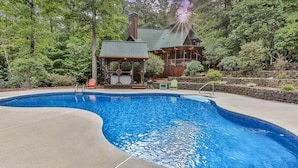 A swimming pool with a wooden deck, a gazebo, and a house with a green roof. - Mountain Pooladise | Blue Ridge, Ga (Epworth)