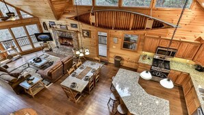 Eine Hütte mit Essbereich, Küche und Wohnzimmer, inklusive Kamin.