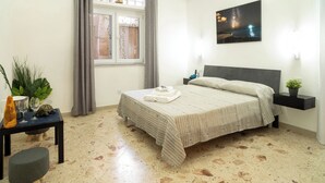 A bedroom with a bed, a nightstand, a window with curtains, a wall-mounted air conditioner, and a painting. - Notti Magiche (Santa Maria di Castellabate)