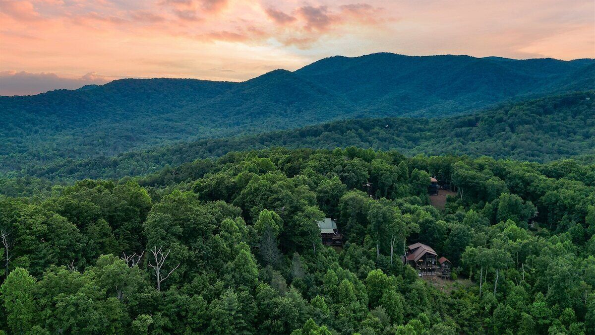 A forested mountain landscape with a cabin.