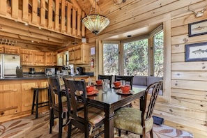 L’intérieur d’une cabane en bois comprend un coin repas, une cuisine et de grandes fenêtres.