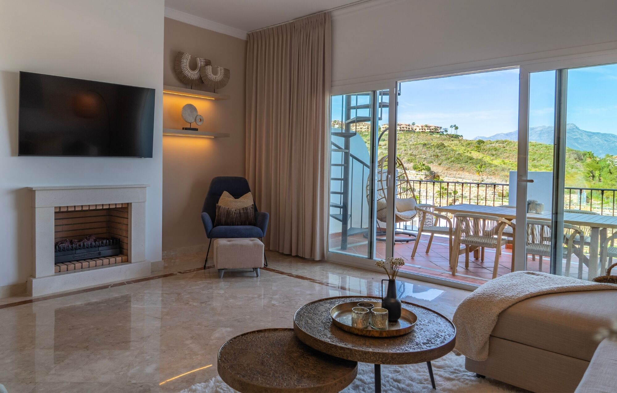 Un salon moderne doté d’une cheminée, d’un téléviseur à écran plat et d’un balcon aménagé avec du mobilier d’extérieur.