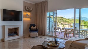 A modern living room with a fireplace, a flat-screen TV, and a balcony with outdoor furniture.