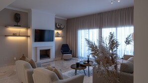 A modern living room with a fireplace, comfortable seating, and a large window with curtains.