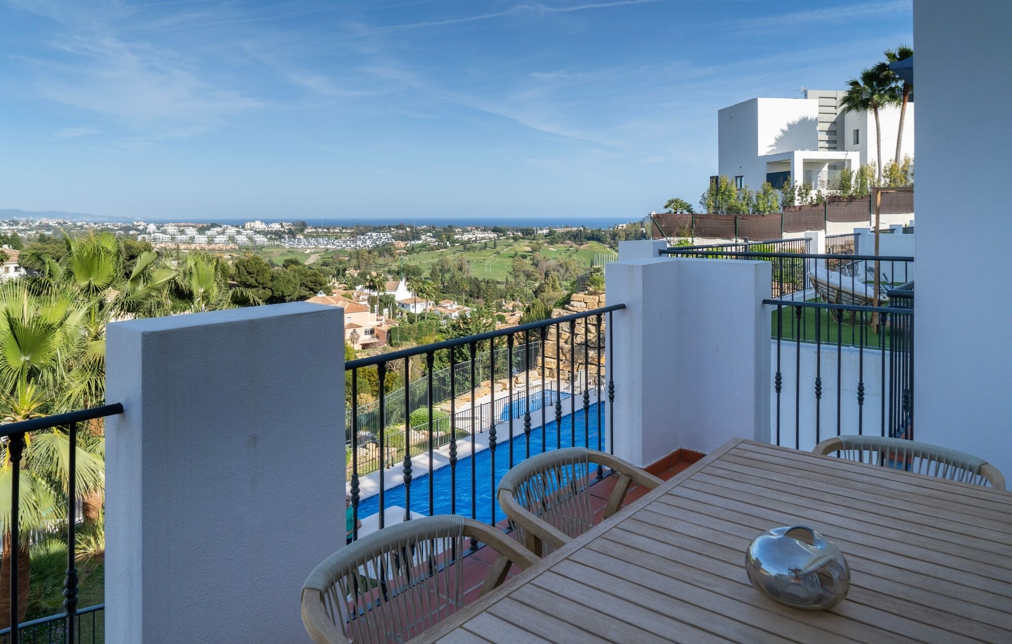A balcony with a view of a swimming pool and a distant landscape.