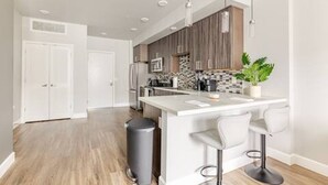 A modern kitchen with a central island, bar stools, and a potted plant. - Mid-rise Modern Lux loft In The City (Sacramento)