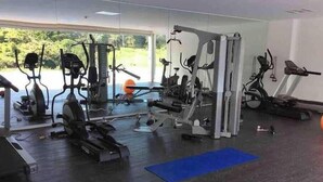 A gym with various exercise machines, a blue mat, and a view of greenery outside. - Penthouse safe and beautiful, with stunning views (San José)