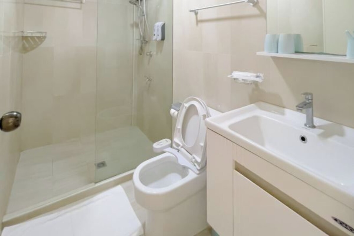 A bathroom with a toilet, sink, and glass shower enclosure.