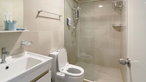 Un baño moderno con lavamanos blanco, inodoro y ducha con mampara de vidrio.