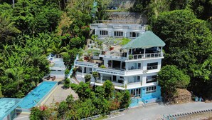 Un resort de varios pisos con piscina, rodeado de exuberante vegetación.
