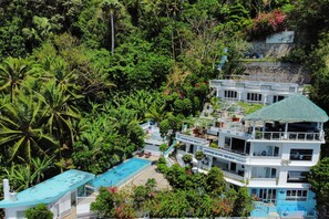 Ein mehrstöckiges Resort mit Pool, umgeben von üppiger Vegetation und Palmen.