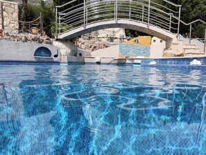 A swimming pool with a stone wall and a metal bridge. - Holiday Home  Mermaid (Mihanici)