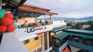 A hotel with a balcony, outdoor seating, and a view of mountains. - Upgrace Inn Coron (Coron)