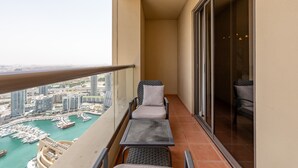 Un balcon avec deux chaises et une table, donnant sur une marina où l’on peut admirer des bateaux et des bâtiments.