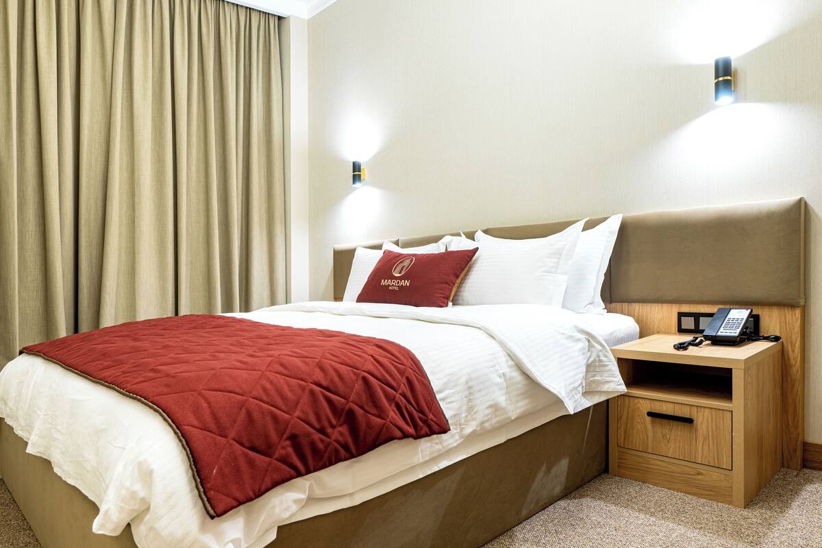 A hotel room with a bed, a nightstand, and a telephone.
