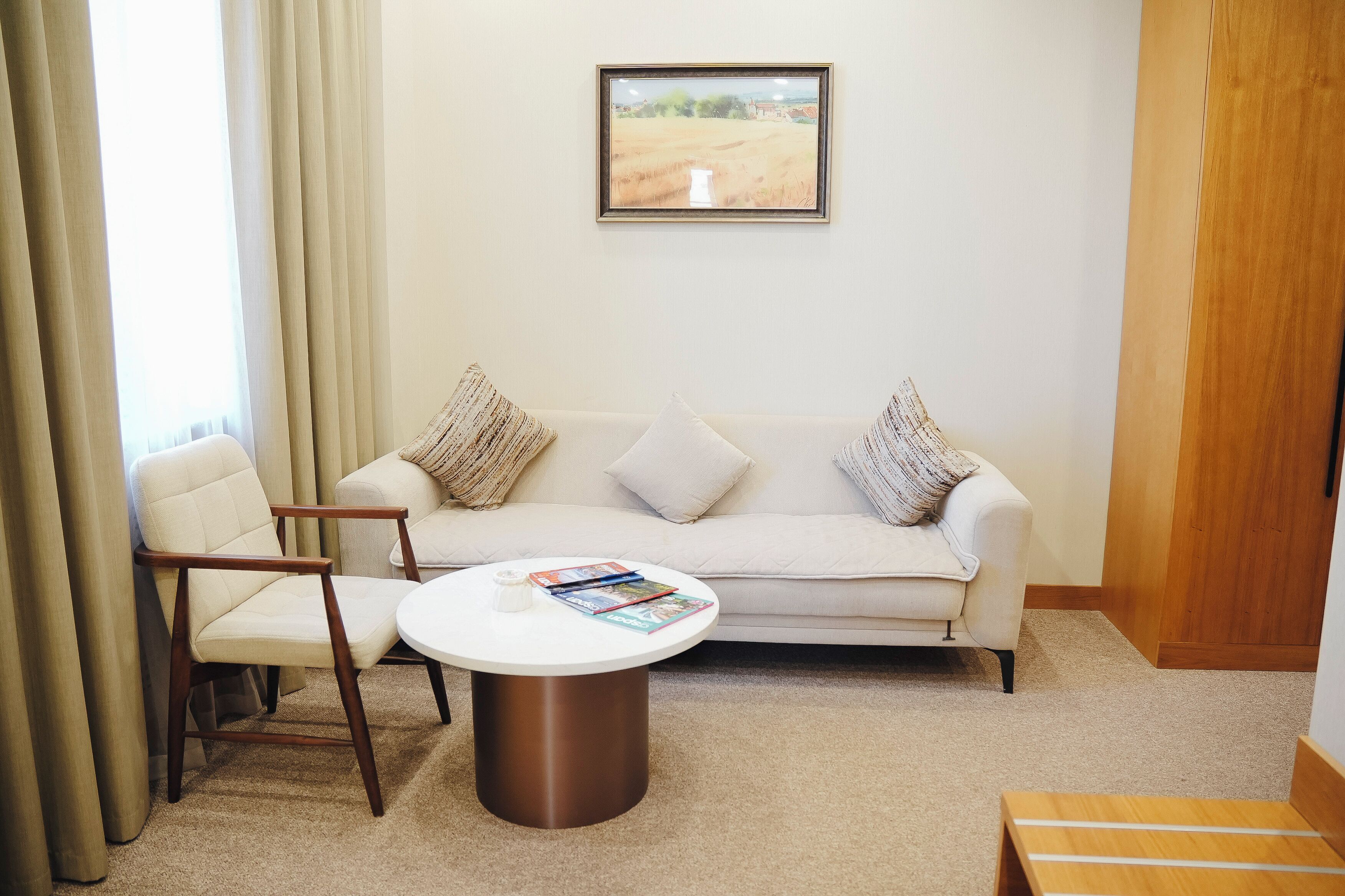Una habitación con sofá, dos sillones, una mesita de centro y un cuadro enmarcado en la pared.