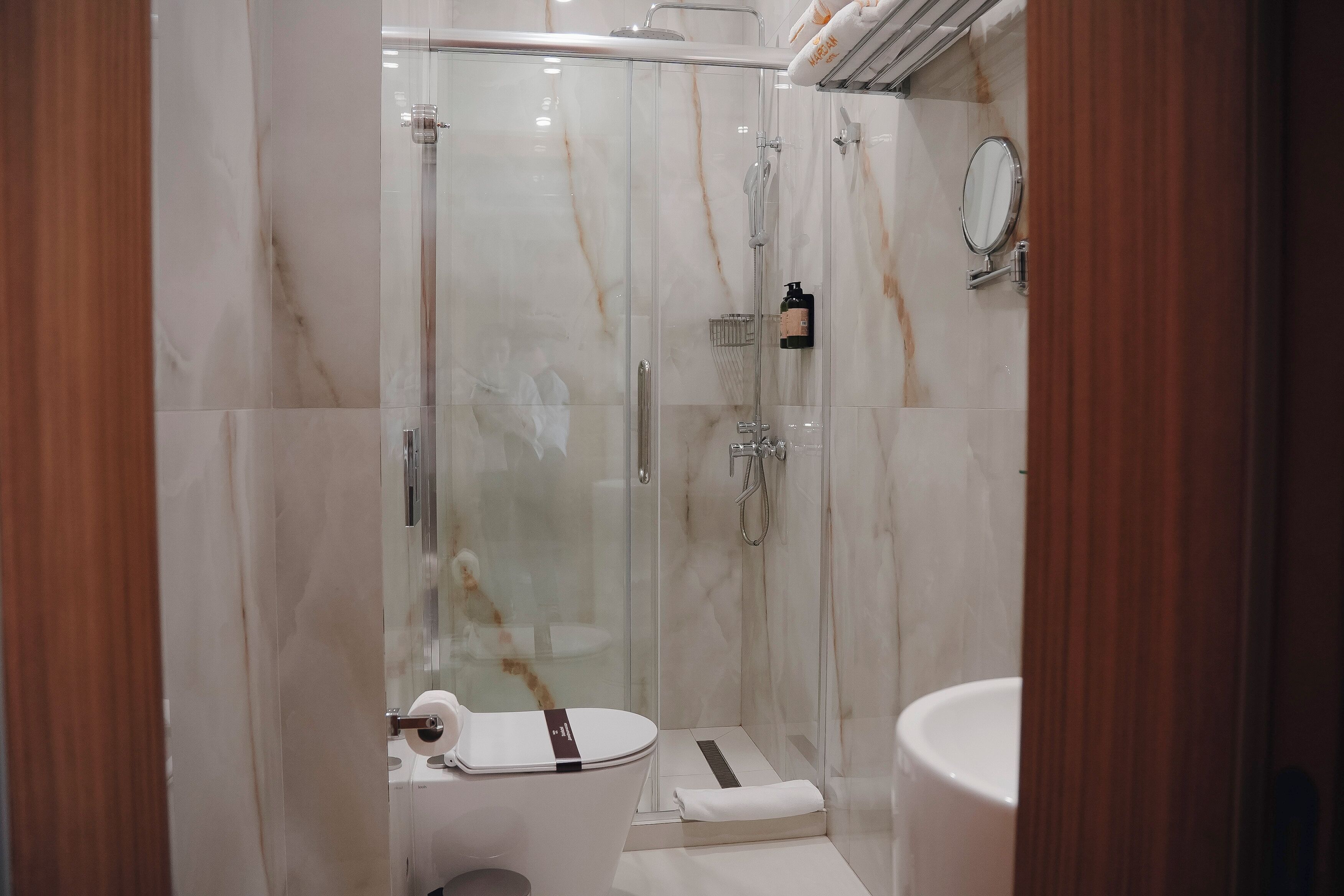 A modern bathroom with a glass-enclosed shower, a toilet, and a sink.