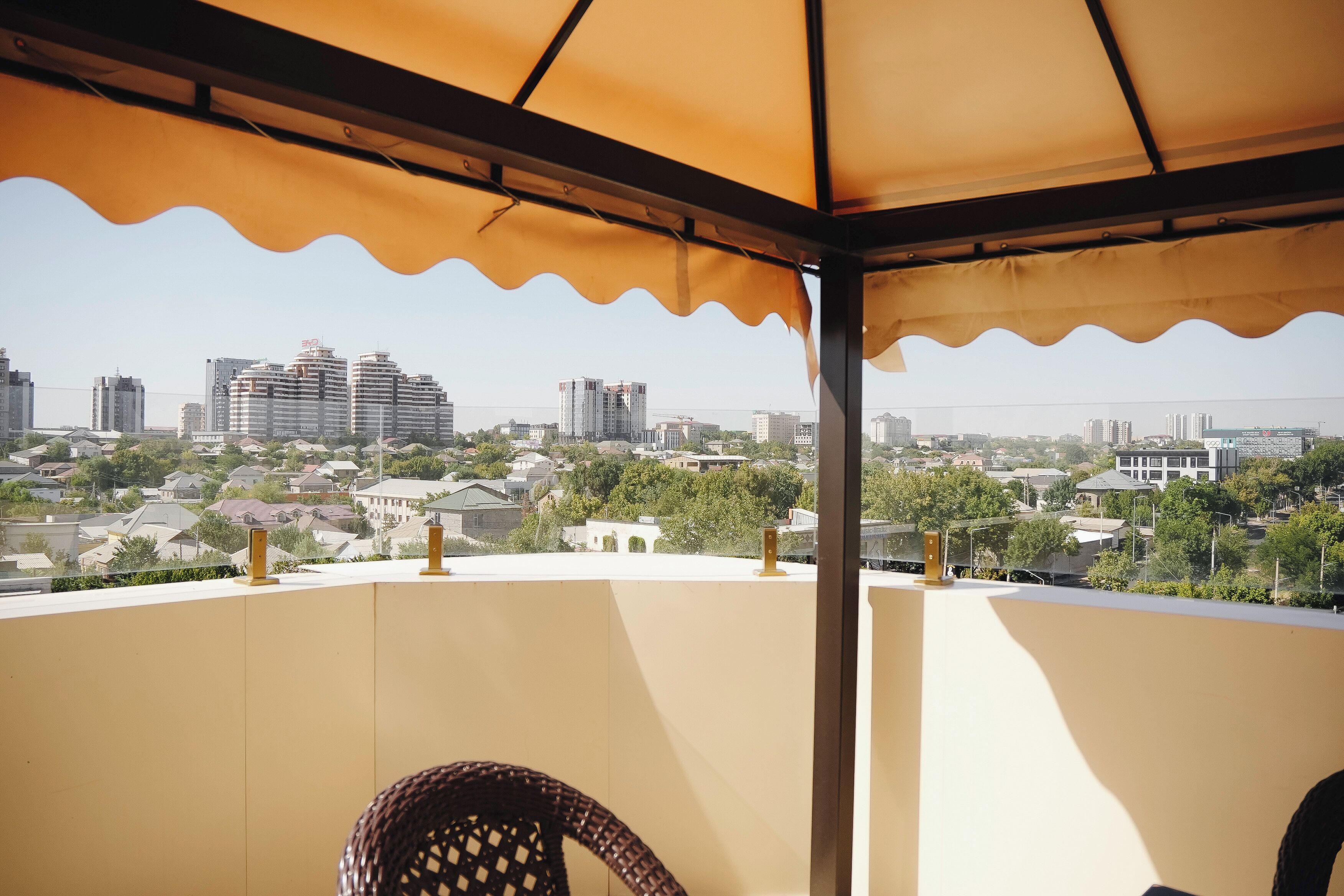 A covered balcony with a view of a cityscape, including high-rise buildings and residential houses.