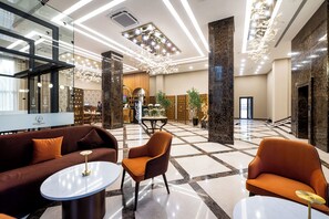A spacious lobby with a modern design, featuring a sofa, armchairs, and a coffee table. - Mardan Hotel (Shymkent)
