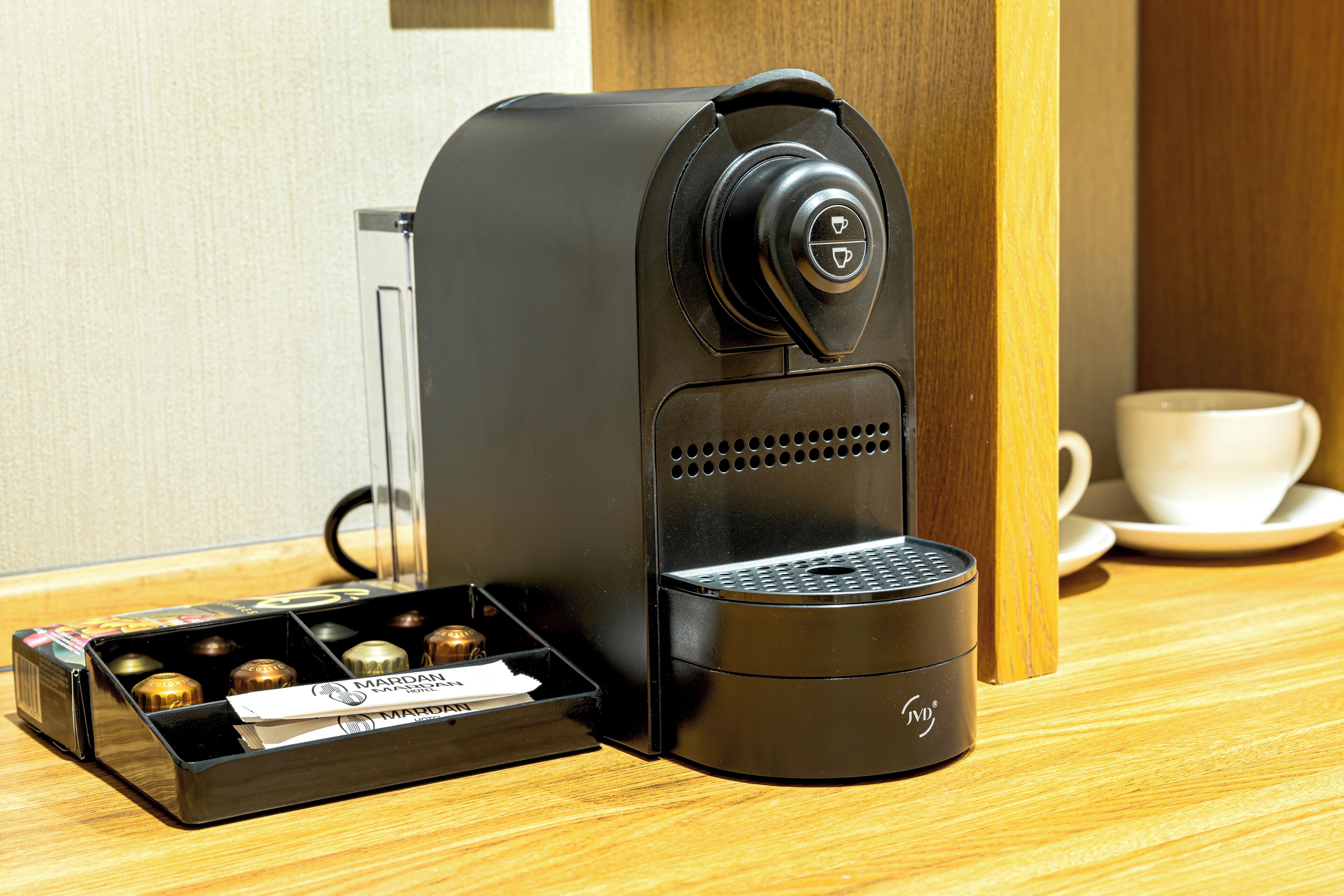 A coffee machine with a coffee pod holder and a cup on the table.
