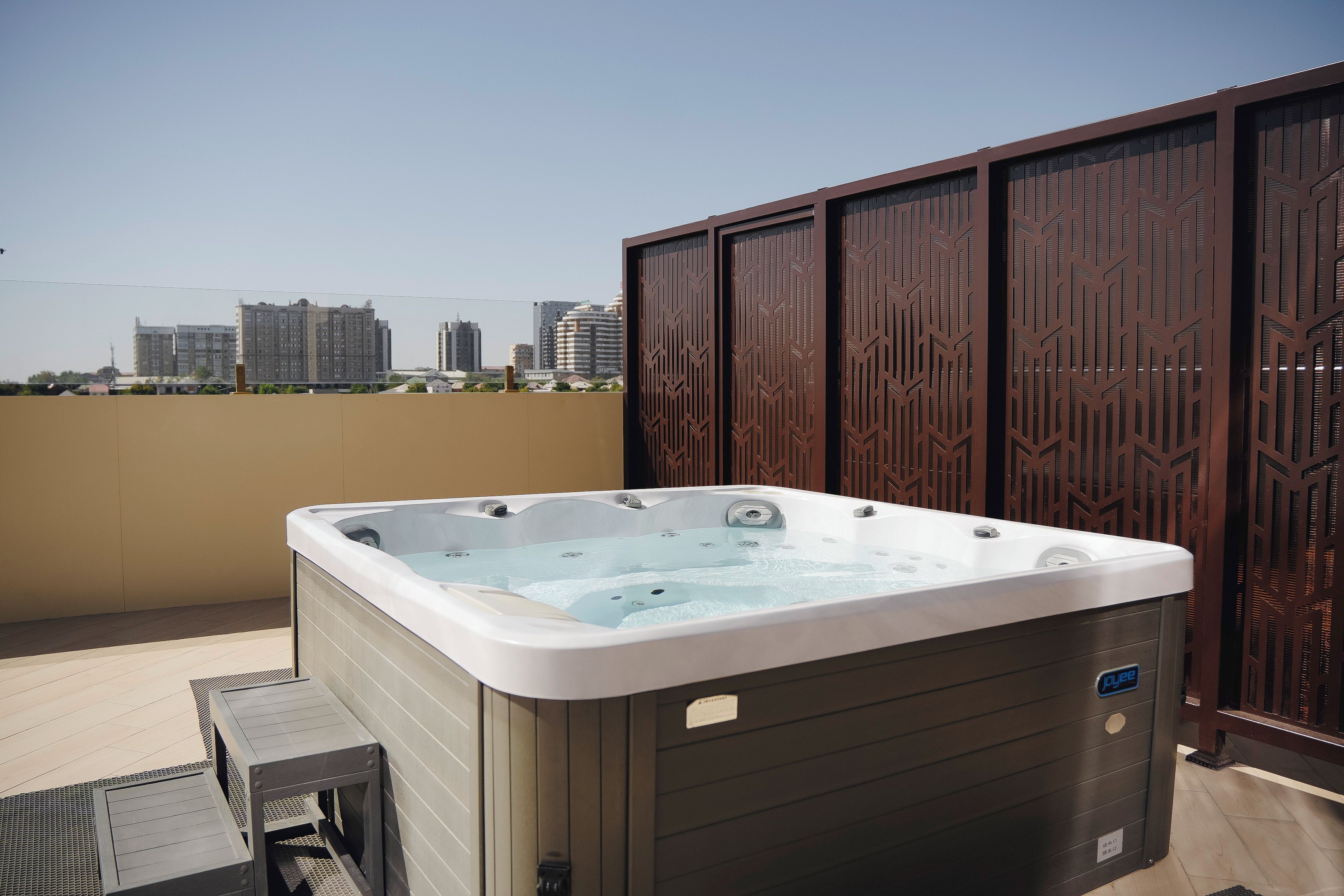 A hot tub on a balcony with a cityscape view.