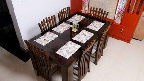 Une table à manger entourée de six chaises en bois, chacune recouverte d’une nappe à motifs floraux.