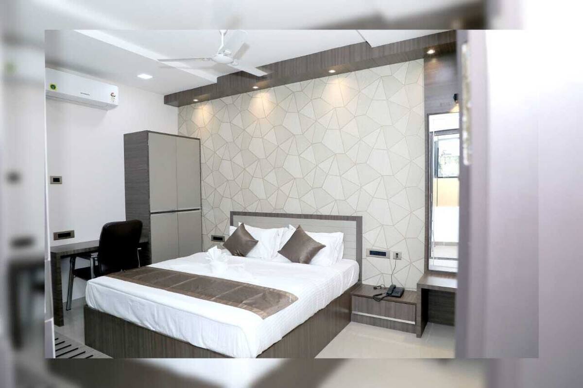 A modern hotel room with a large bed, a desk, and a wardrobe.