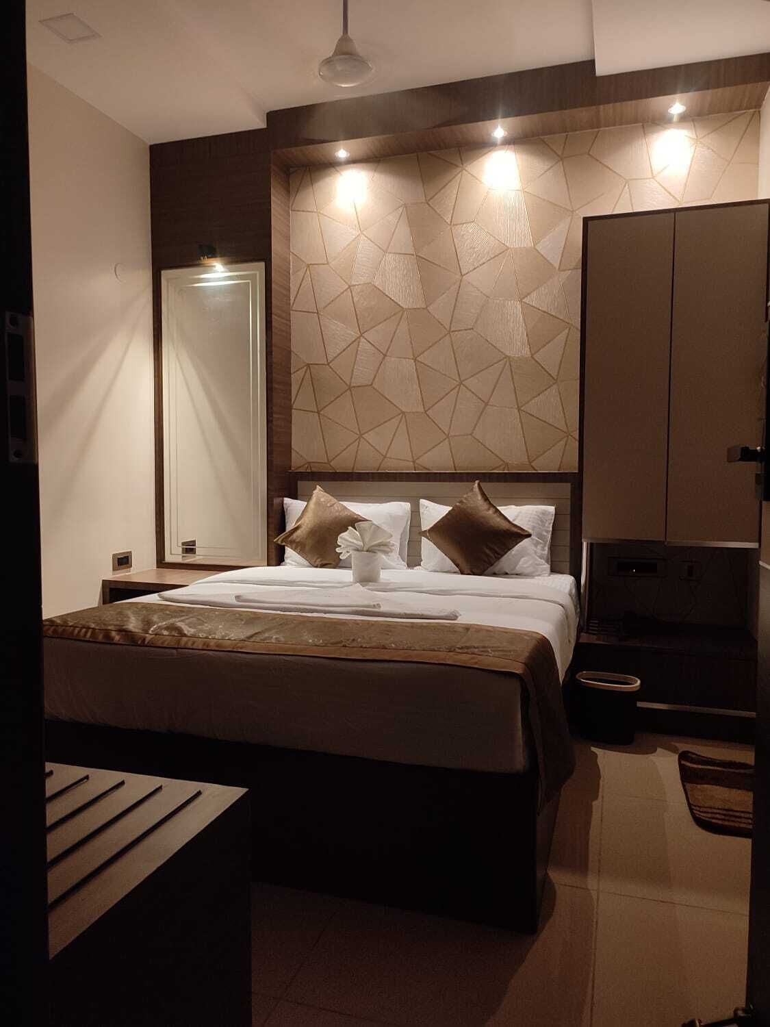 A modern hotel room with a large bed, a wardrobe, and a mirror.