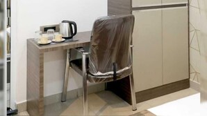 A small kitchenette with a built-in stove, a chair, and a cabinet. - HOTEL RSB PLAZA  (Tirupur)
