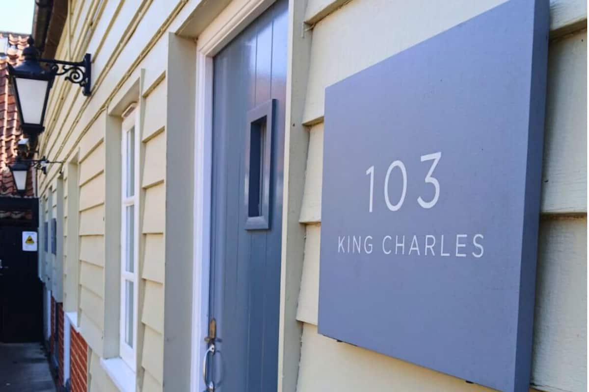 A house number sign with the number 103 and the name 'King Charles' on a building facade.