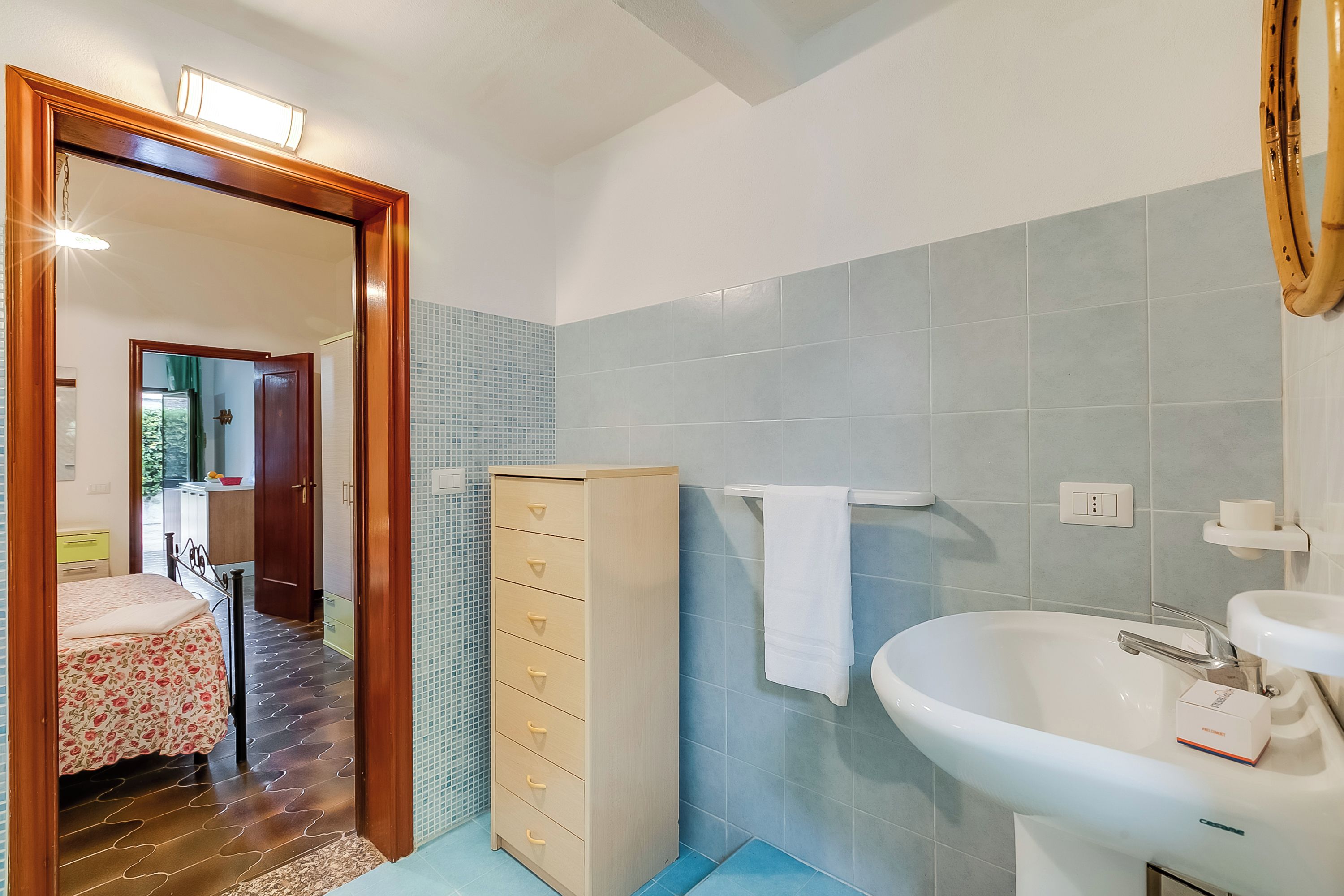 Een badkamer met een wastafel, spiegel en een houten kastje.
