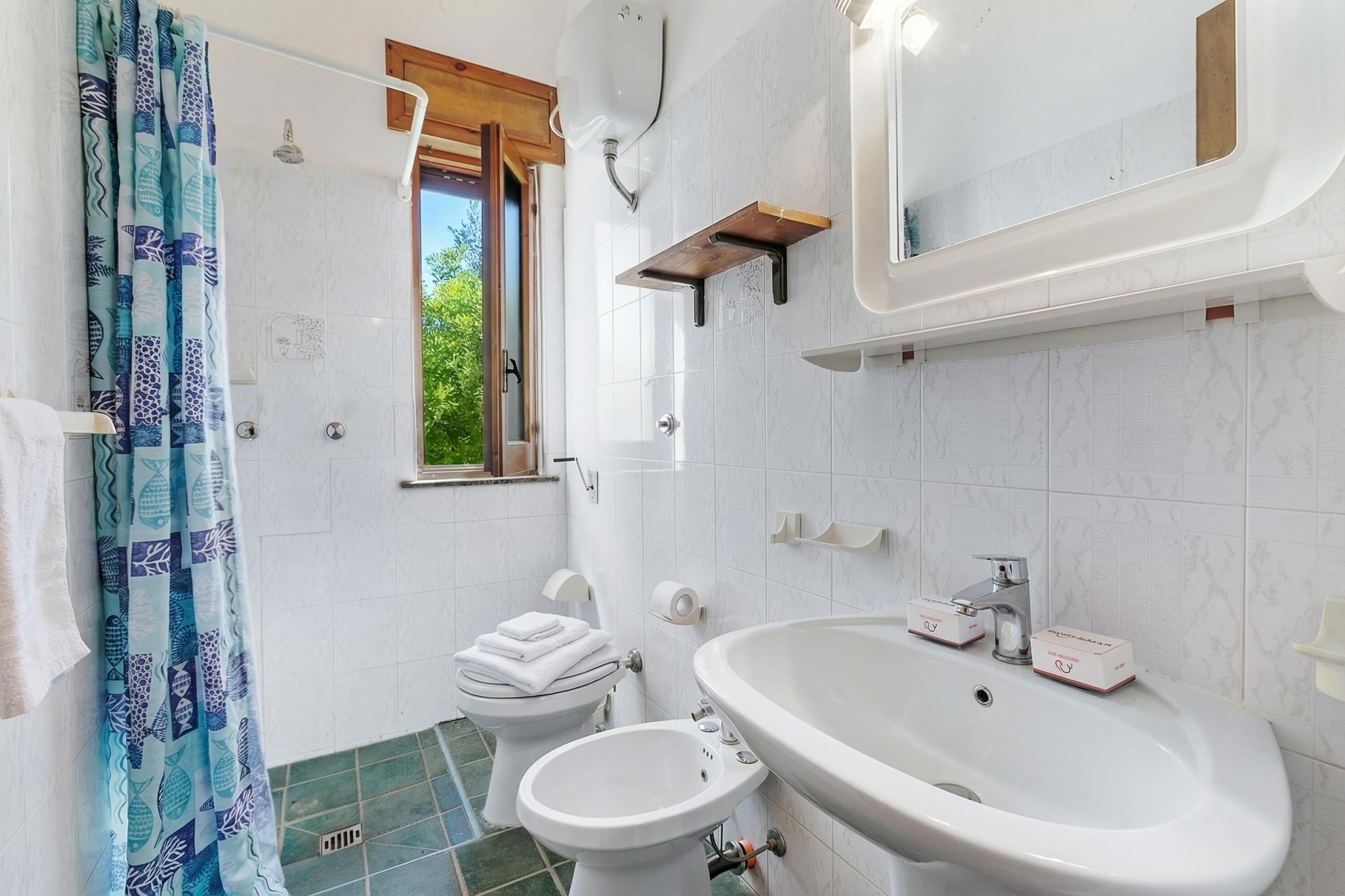 Un baño con inodoro, bidé, lavabo y ducha.