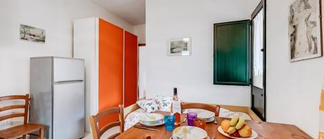 A compact living space with a dining area, a refrigerator, and a door with a green panel.