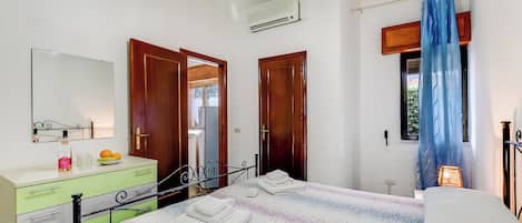 A bedroom with a bed, a dresser, a mirror, and a window with curtains.