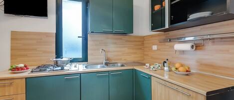 Cozinha moderna com armários verde-água, pia de aço inoxidável e janela.