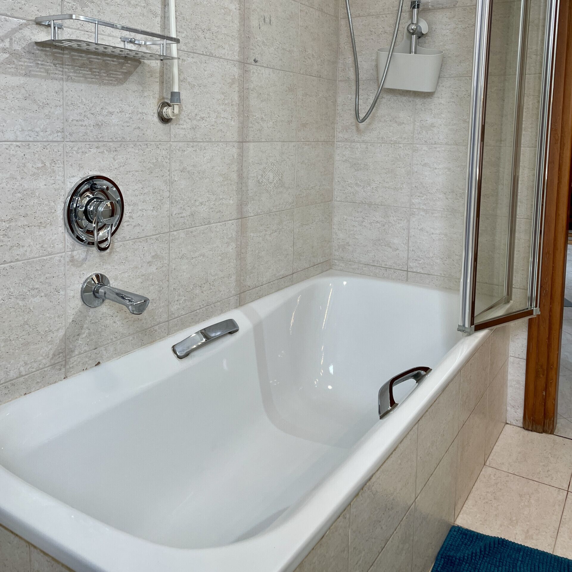 Een moderne badkamer met een vrijstaand bad, een handdouche en een douche met glazen wanden.