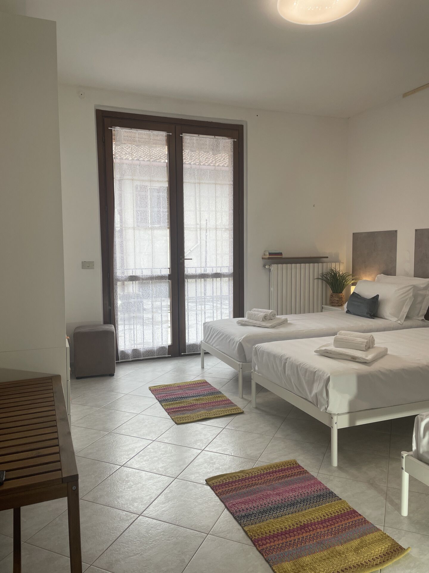Een moderne slaapkamer met twee bedden, een tafeltje en een bankje.