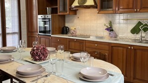 Uma cozinha com armários de madeira, bancada de mármore e uma mesa de jantar posta com pratos e copos.