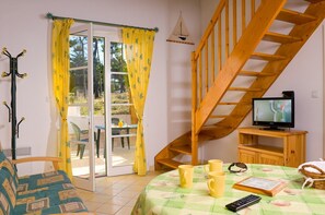 Enjoy a comfortable stay in this inviting room with a TV on the upper level, a sliding glass door, and a cozy table setting.