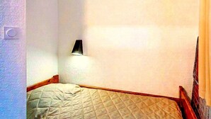 Ein Schlafzimmer mit einem Bett, einer Wandleuchte und einer Tür.