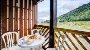 Eine Holterrasse mit Frühstückstisch, mit Blick auf eine hügelige Landschaft.