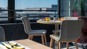 Un comedor con una mesa dispuesta para dos, una jarra de jugo de naranja, una taza de café y un plato de comida.