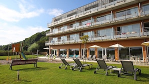 Un hotel de varios pisos con terraza y un parque infantil.