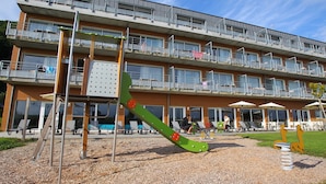 Un edificio de varios pisos con balcones, mobiliario exterior y un parque infantil.